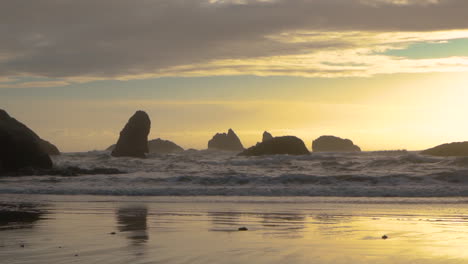 Slow-motion-waves-coming-ashore-during-a-beautiful-sunset-at-the-Oregon-Coast-in-Bandon,-Face-Rock-Beach-State-Park