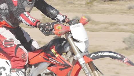 SLOW-MOTION:-A-dirt-biker-rides-his-red-motorcycle-through-the-desert-from-left-to-right