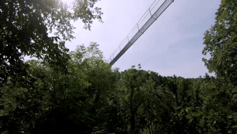Moving-shot-of-a-suspension-bridge-over-a-forested-gorge-in-Monthey,-Switzerland