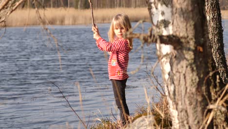 Girl-playing-with-stick-close-to-the-water