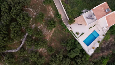 Aerial-Birds-Eye-Flyover-of-Luxury-Greek-Villa-located-in-Rural-Crete-Countryside-with-Surrounding-Green-Foliage