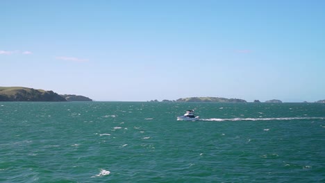 Bewegende-Aufnahme-Eines-Kleinen-Bootes-Auf-Türkisfarbenem-Wasserozean-Mit-Kleinen-Inseln-Im-Hintergrund,-Neuseeland