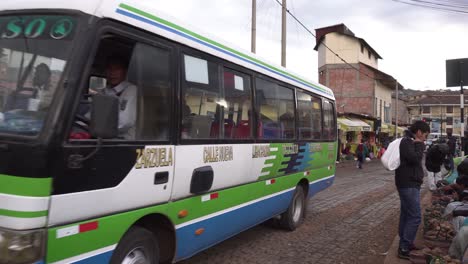 Bus-on-public-street-in-Cusco-with-many-locals-selling-on-market,-Peru