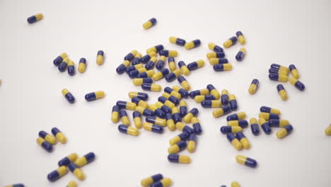 Slow-Motion-of-Blue-and-Yellow-Pills-Dropped-onto-White-Background