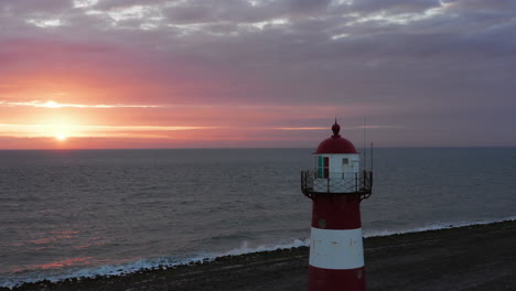 The-lighthouse-of-Westkapelle-during-a-bright-orange-sunset,-with-a-lot-of-wind