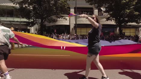US-Bank-employees-participating-in-the-Seattle-LGBTQ-parade,-waving-a-giant-rainbow-flag