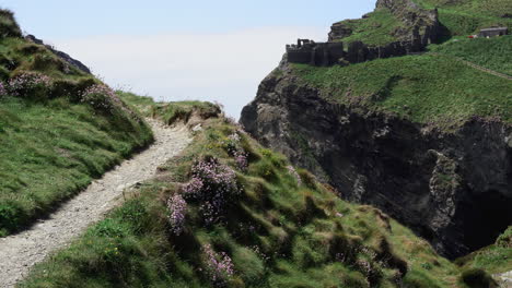 Tourist-Im-Urlaub-Zu-Fuß-Auf-Einer-Klippe-Entlang-Des-Pfades,-Der-Zu-Den-Ruinen-Von-Tintagel-Castle-In-Cornwall-Führt