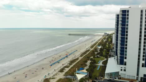 Aerial-push-in-shot-toward-Myrtle-Beach-coastline-past-large-building-during-midday