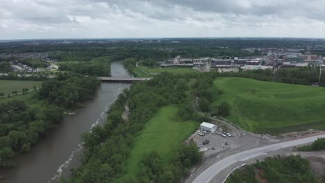 Drone-rises-over-river-and-looks-toward-a-highway-and-a-small-Midwestern-city-in-the-distance
