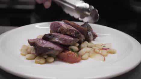 Chef-Usando-Un-Cuchillo-Para-Servir-Carne-En-Rodajas-Y-Frijoles-Con-Rábanos