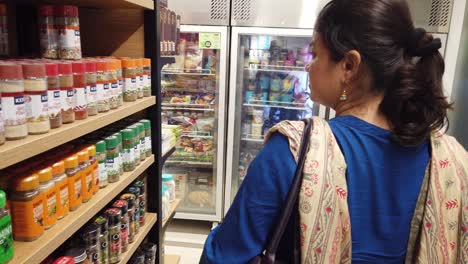 Young-Indian-Lady-is-Shopping-at-a-Grocery-Shop-and-Browsing-through-Various-Products-during-Grocery-Purchases