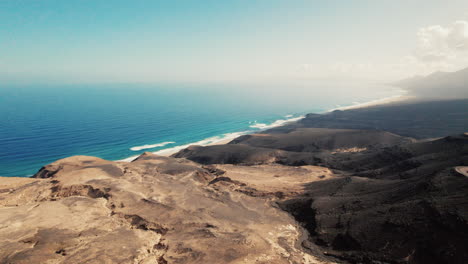 Aerial-view-of-dramatic-coastal-landscape-of-Fuerteventura,-panoramic-vista-of-Playa-de-Cofete-in-background-with-azure-Atlantic-coean