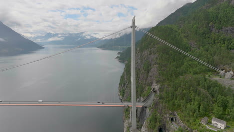 Hardanger-Bridge-with-tall-tower-suspension-design,-road-tunnel-entering-mountain,-aerial