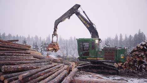 Industrial-timber-manipulator-logging-machine-sorting-piles-of-wood-in-snowstorm