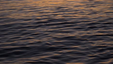 Reflection-of-sunset-on-calm-ocean-water-in-slow-motion