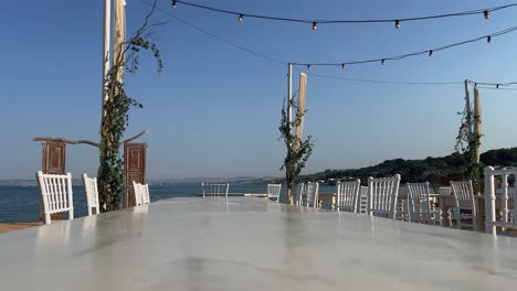 Waterfront-wooden-door-and-empty-table-with-chairs-on-beach-for-celebration-venue
