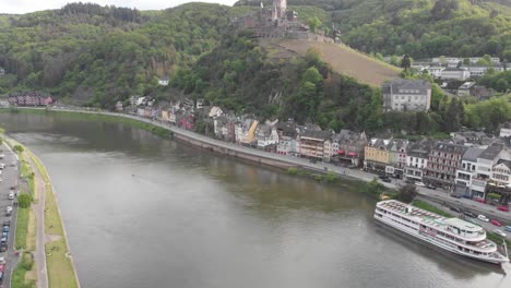 Static-establishing-shot-over-the-Moselle-River-as-a-cruise-ships-docked-at-the-city-of-Cochem,-popular-tourist-destination-in-Europe,-Germany
