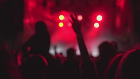 Blurry-view-of-music-festival-fans-and-flashing-red-and-white-lights-on-stage,-live-concert