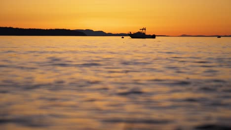 Wide-shot-of-small-boat-on-calm-ocean-at-sunset-in-slow-motion