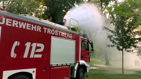 Deutsches-Feuerwehrauto,-Das-An-Einem-Heißen-Sommertag-Wasser-Für-Kinder-Und-Bäume-Sprüht-7