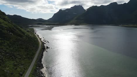 Aerial-view-of-street-winding-the-dramatic-landscapes-of-northern-europe's-paradise-islands-Lofoten-in-Norway-with-view-over-the-sea-and-the-mountains