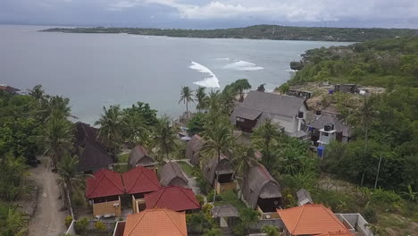 Flyover-of-cliff-top-tourist-resort-on-Bali,-and-Indian-Ocean-beyond