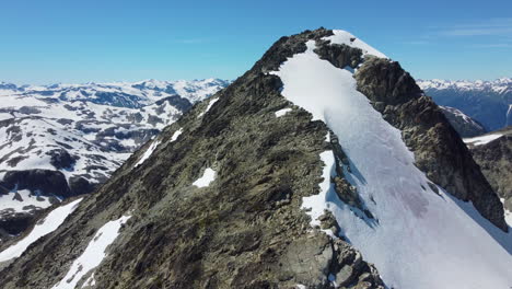 Incredible-Mountain-Peak-Reveal-Over-Rocky-Landscape-with-Blue-Sky-near-Pemberton-Meadows-Canada---Aerial-Drone-Footage