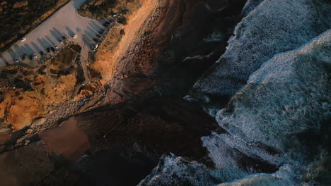 Top-down-drone-shot-of-waves-and-coastline-at-sunset