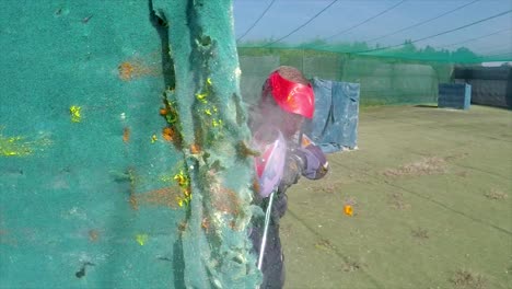 Paintballer-hiding-behind-wall-while-balls-exploding-on-it