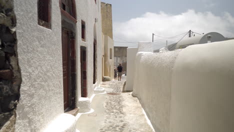 Following-a-man-walking-down-a-narrow-street-of-a-Greek-island