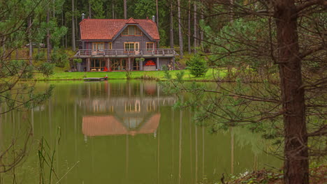Tilt-down-shot-of-beautiful-lakeside-lodge-along-spring-landscape-beside-a-lake-in-timelapse