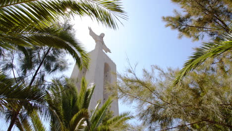 Sun-Shines-Through-Palm-Trees-at-Christ-The-King-Monument-in-Almada