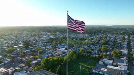 American-flag-waves-over-American-city-during-sunset-light
