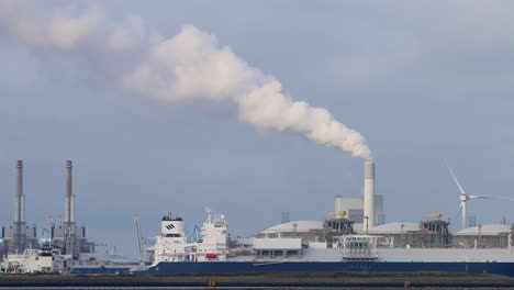 Large-commercial-ship-in-dock-with-chimney-emitting-steam-or-smoke-in-the-background