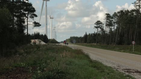 A-line-of-wind-turbines-at-a-gavel-road-with-trees