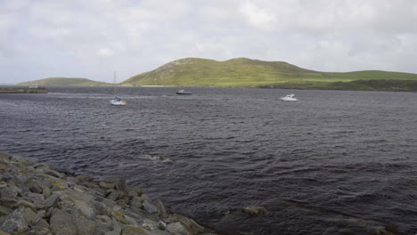 Toma-Estática-De-La-Costa-De-Irlanda-Mirando-3-Barcos-En-Un-Día-Ventoso-En-El-Océano-Atlántico-Y-Una-Isla-En-El-Fondo-En-4k