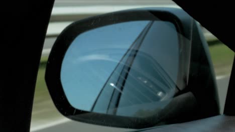 Rear-view-mirror-of-the-car-while-driving-on-the-highway