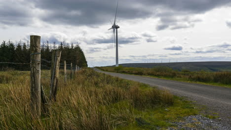 Zeitraffer-Der-Windkraftanlage-In-Der-Ferne-Mit-Fahrenden-Autos-Und-Menschen,-Die-Die-Straße-In-Den-Arigna-Bergen-In-Irland-Hinuntergehen