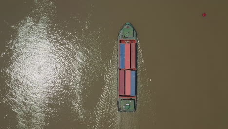 Top-down-view-of-freighter-transporting-shipping-containers-on-a-Southeast-Asian-river