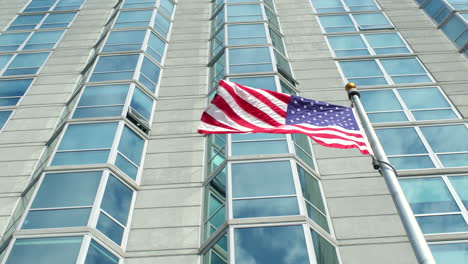 Amerikanische-Flagge-Weht-Im-Wind-Vor-Einem-Wolkenkratzer-In-Zeitlupe