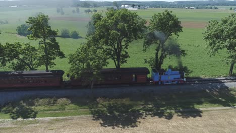 Luftaufnahme-Eines-Thomas-The-Tank-Engine-Mit-Passagierwagen,-Die-Entlang-Der-Amischen-Landschaft-Schnaufen