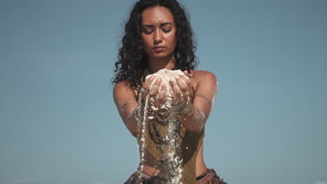 Attractive-eastern-girl-picking-sand-in-palm-and-dissolve-through-fingers-in-slow-motion