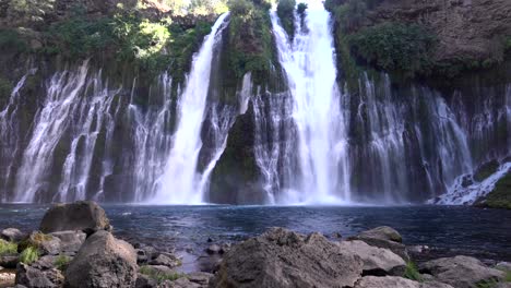 4K-footage-of-Burney-Falls,-with-a-wide-angle-camera-panning-out-to-get-the-whole-picture-of-the-waterfall-cascading-down-to-the-lake-below