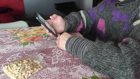 Weiße-Frau-Isst-Erdnüsse-Auf-Einem-Tisch-Und-Benutzt-Handy