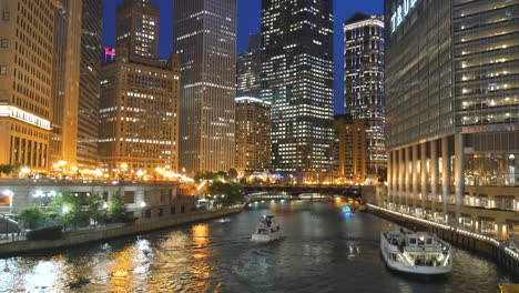 Chicago-riverwalk-view,-boats,-skyscrapers,-towers,-night-and-evening-cityscape-scene,-trump-tower-illuminated