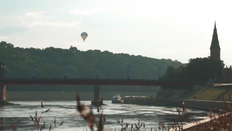 Static-shot-of-hot-air-balloon-and-church-tower-and-bridge-while-sun-is-shining