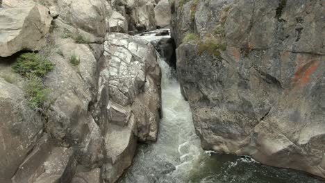 Aerial-dolly-over-river-towards-waterfall-in-canyon-in-Colorado