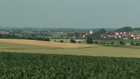 Typical-bavarian-landscape-with-fields-and-village-of-Adelshausen-in-the-back,-Bavaria,-Germany