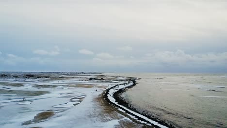 Slow-Flight-over-frozen-Sandgerdi,-Iceland-Golf-Course-and-coast