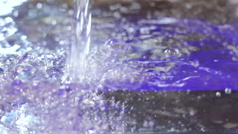 Slow-Motion,-water-is-poured-in-clear-container-creating-refreshing-bubbles-and-surging-underwater